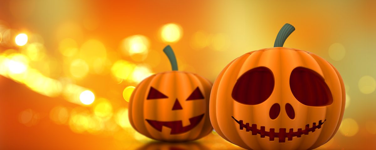 Un ordenador con una calabaza al lado y luces tenues, evocando el ambiente de Halloween con elementos digitales.