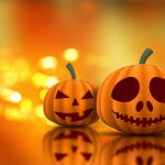 Un ordenador con una calabaza al lado y luces tenues, evocando el ambiente de Halloween con elementos digitales.