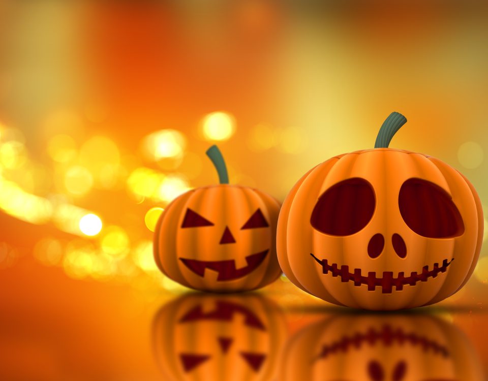 Un ordenador con una calabaza al lado y luces tenues, evocando el ambiente de Halloween con elementos digitales.